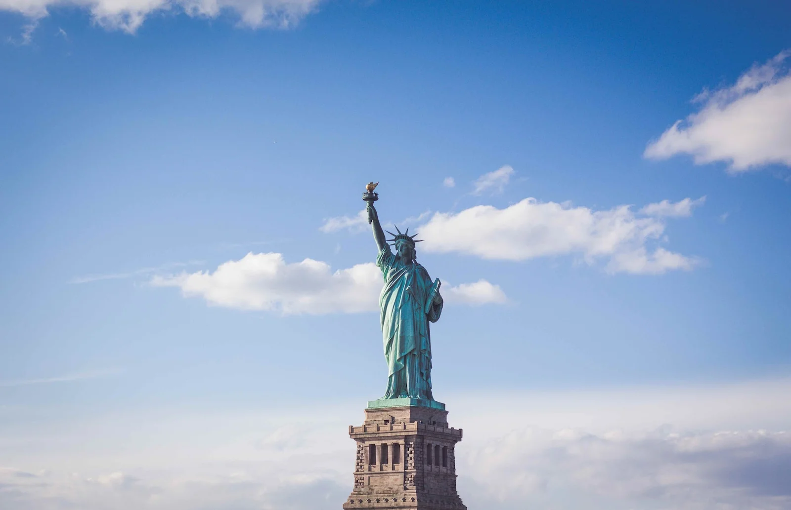 Photo by Ferdinand Stöhr Statue of Liberty, New York under white and blue cloudy skies