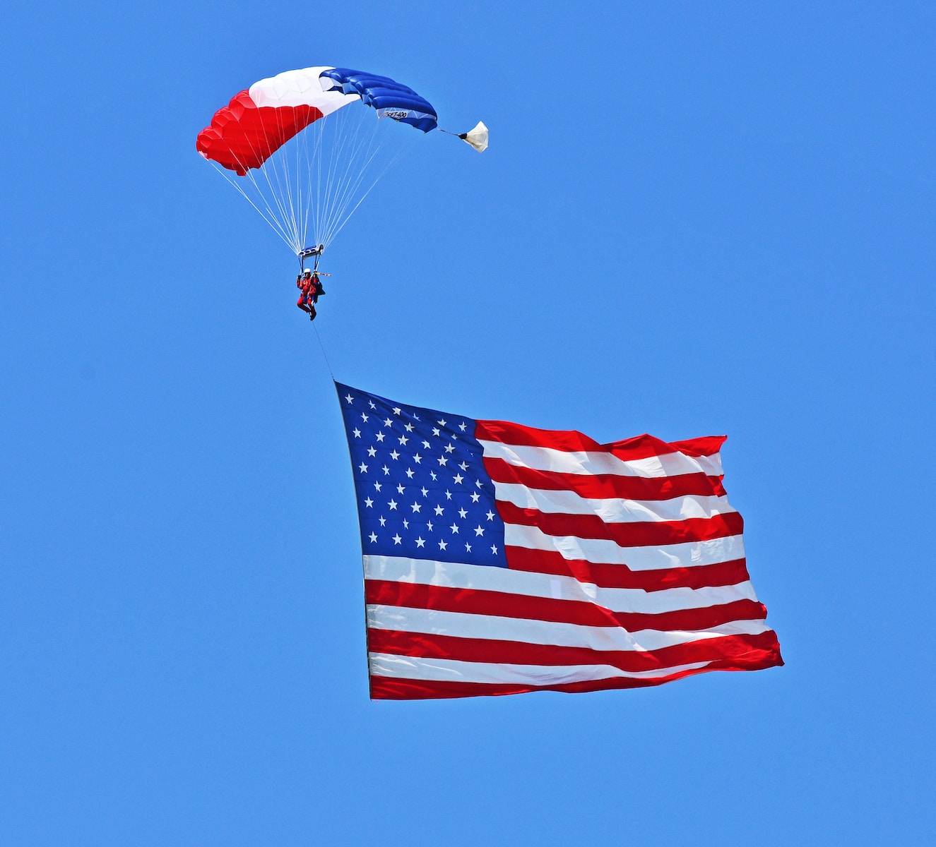 person paragliding with USA flag under blue sky