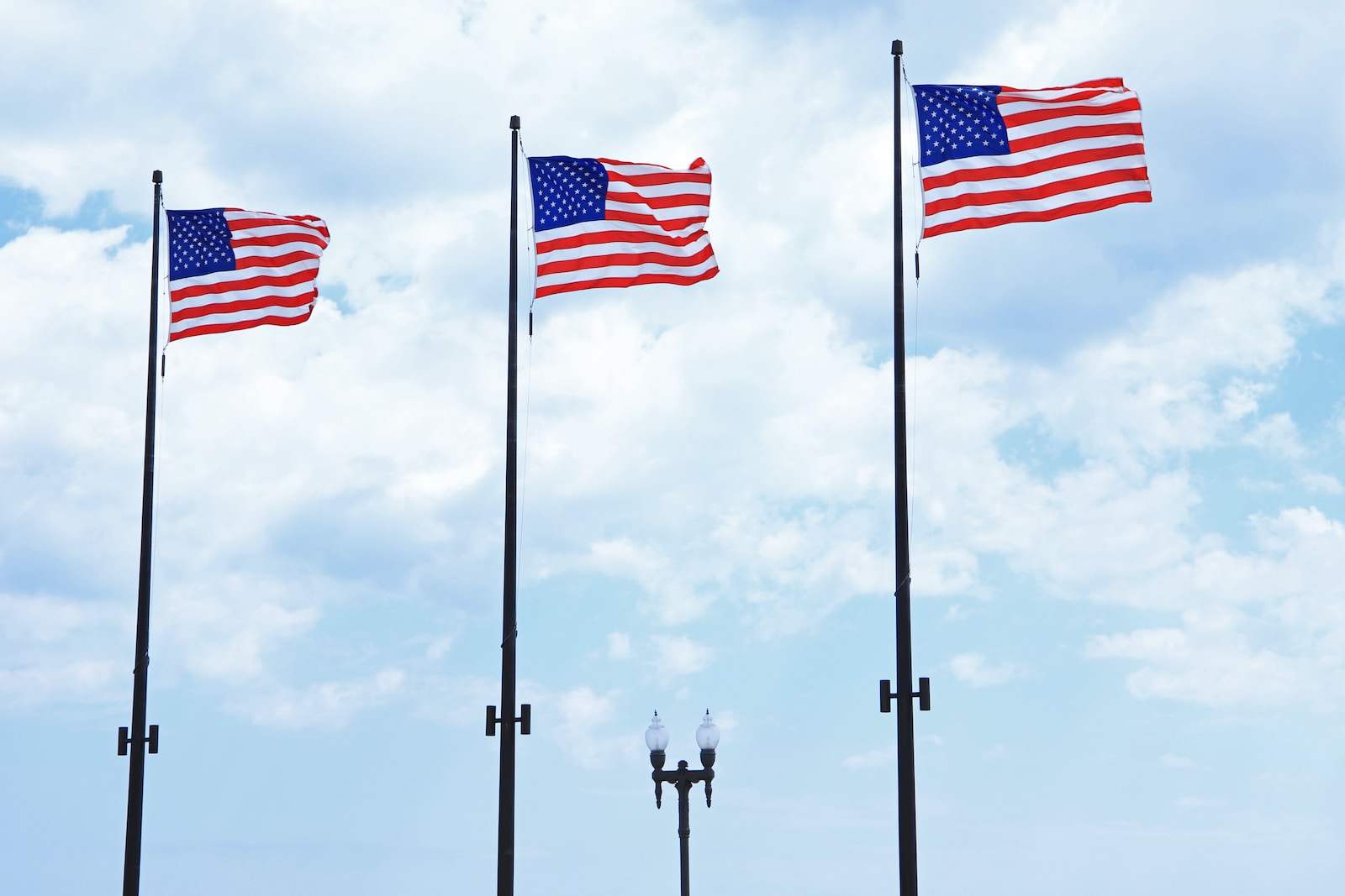 three american flags are flying in the wind